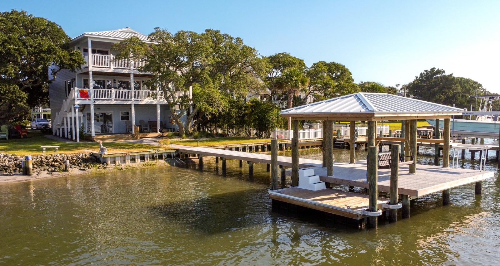 A large soundfront vacation home in Surf City, NC, featuring a long private wooden dock leading to a covered gazebo over the water.